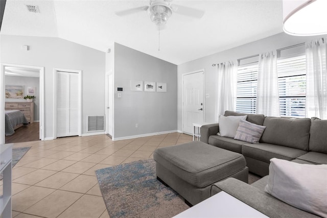 living area featuring light tile patterned floors, visible vents, and vaulted ceiling