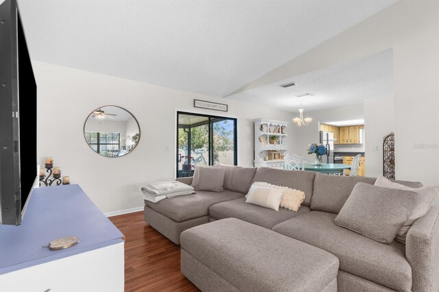 living room featuring baseboards, lofted ceiling, a notable chandelier, and wood finished floors