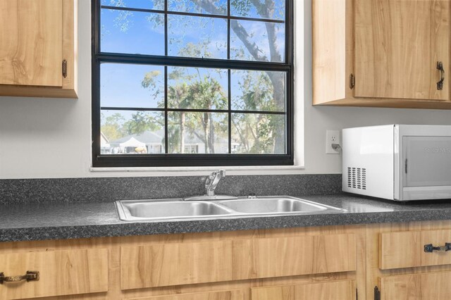 kitchen featuring a sink, dark countertops, and light brown cabinetry