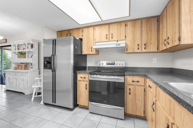 kitchen featuring under cabinet range hood, dark countertops, appliances with stainless steel finishes, and light tile patterned floors