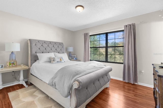 bedroom featuring wood finished floors, baseboards, and a textured ceiling