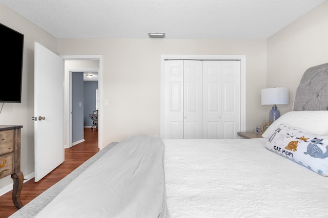 bedroom with visible vents, baseboards, a closet, a textured ceiling, and dark wood-style flooring