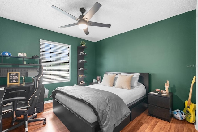 bedroom with a textured ceiling, wood finished floors, and a ceiling fan