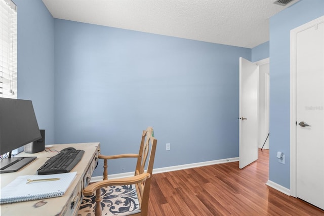 office area featuring a textured ceiling, baseboards, and wood finished floors