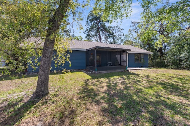 rear view of property featuring a lawn, a shingled roof, and a sunroom