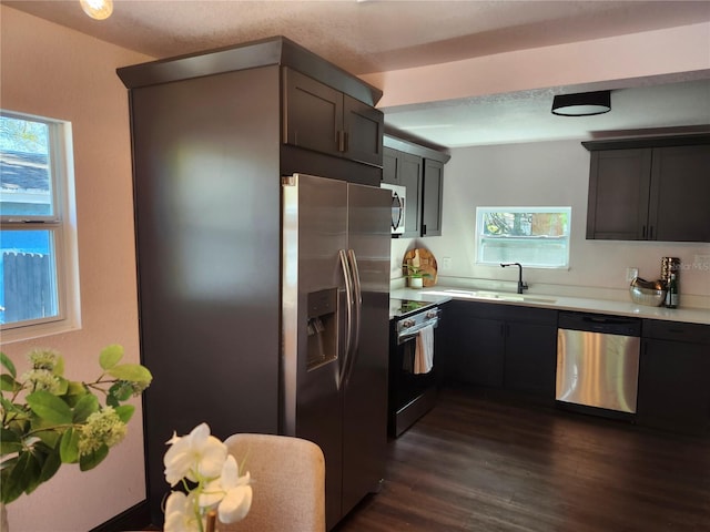 kitchen featuring light countertops, dark wood-type flooring, appliances with stainless steel finishes, and a sink