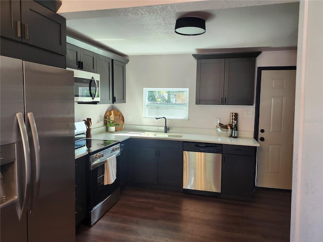 kitchen featuring a sink, light countertops, dark wood-style flooring, and stainless steel appliances