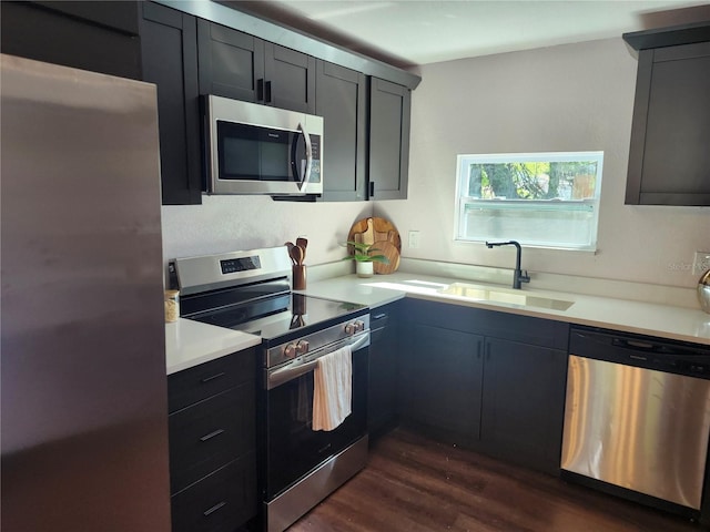 kitchen with a sink, stainless steel appliances, dark wood-style flooring, and light countertops