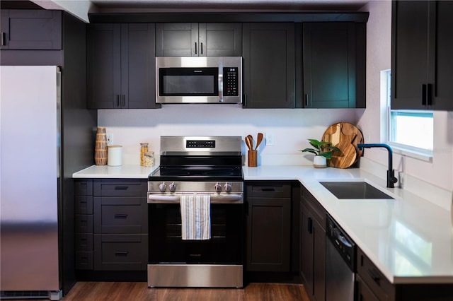 kitchen featuring light countertops, dark wood-type flooring, appliances with stainless steel finishes, and a sink