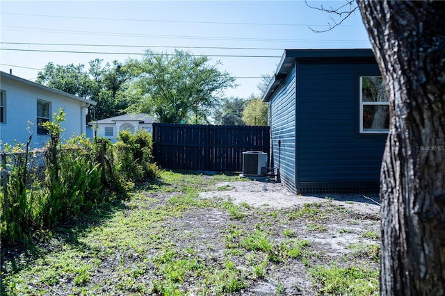 view of yard with central AC and fence