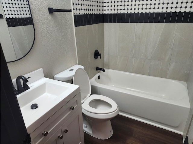 bathroom with vanity, wood finished floors, toilet, and a textured wall