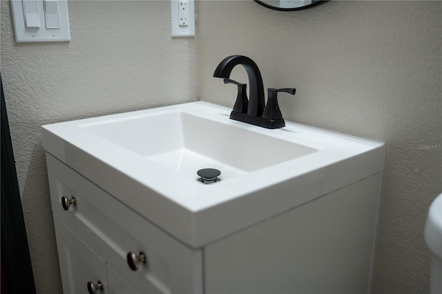 interior details with vanity and a textured wall