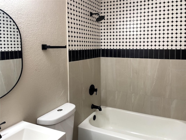 full bath with toilet, a textured wall, and shower / washtub combination