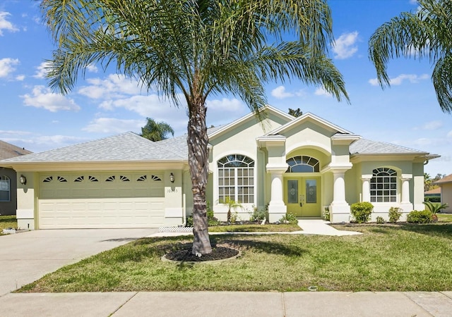 view of front of home featuring a front lawn, a garage, driveway, and stucco siding