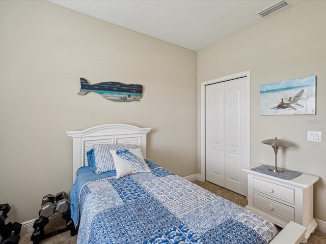 carpeted bedroom with visible vents, baseboards, and a closet