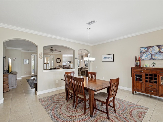 dining space with light tile patterned floors, visible vents, baseboards, arched walkways, and crown molding