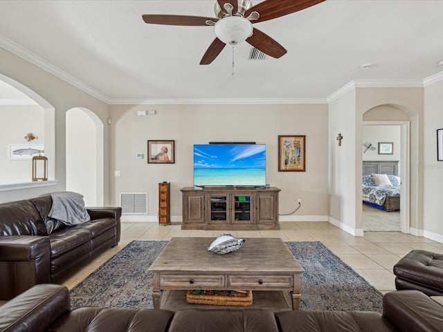 living area with light tile patterned floors, a ceiling fan, baseboards, visible vents, and ornamental molding