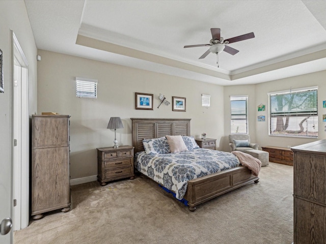 bedroom with light carpet, baseboards, and a tray ceiling