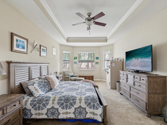 bedroom with light carpet, ornamental molding, a tray ceiling, baseboards, and ceiling fan