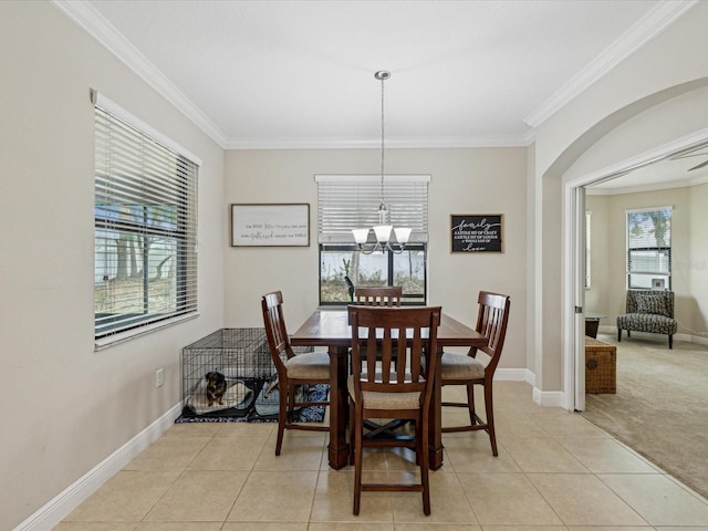 dining area featuring a notable chandelier, ornamental molding, light tile patterned floors, baseboards, and light colored carpet