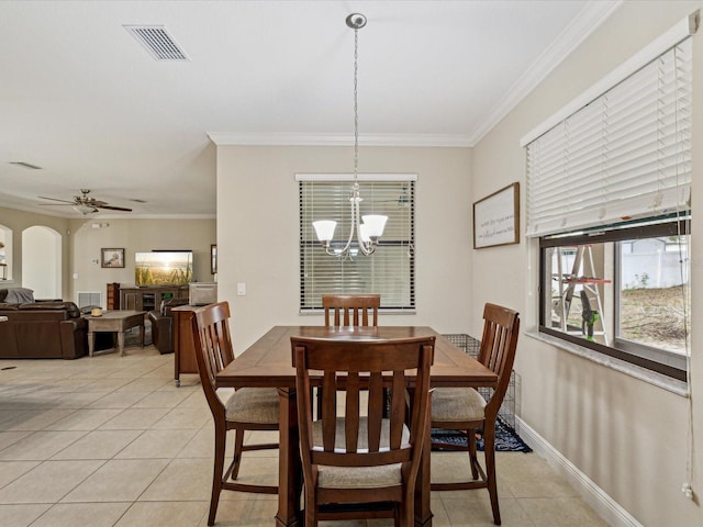 dining area featuring light tile patterned floors, visible vents, arched walkways, and crown molding