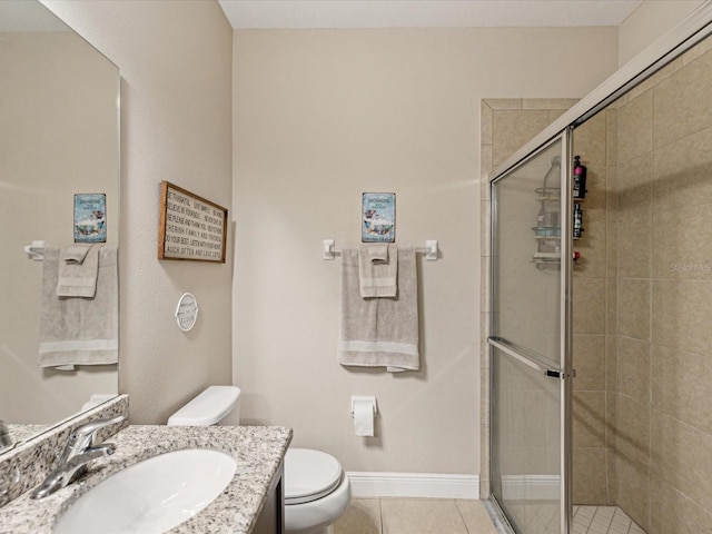 bathroom featuring tile patterned floors, toilet, a stall shower, baseboards, and vanity