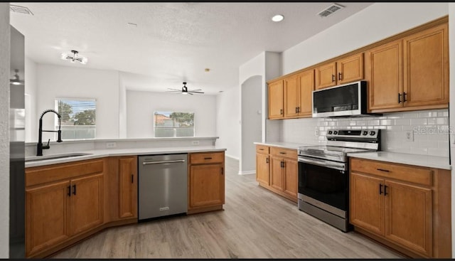 kitchen with visible vents, a sink, light wood-style floors, appliances with stainless steel finishes, and decorative backsplash