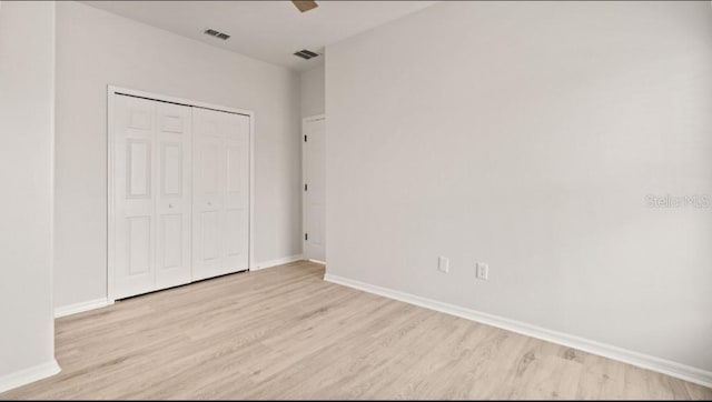 unfurnished bedroom featuring visible vents, baseboards, a closet, and wood finished floors