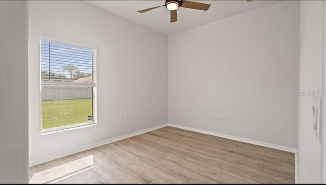 spare room featuring baseboards, wood finished floors, and a ceiling fan