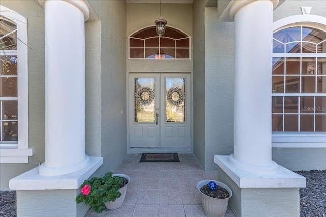 view of exterior entry featuring stucco siding and french doors