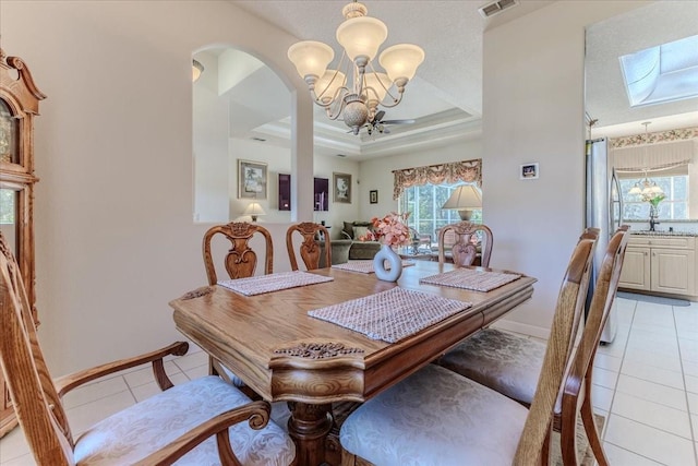 dining room featuring a wealth of natural light, a notable chandelier, a tray ceiling, and light tile patterned flooring