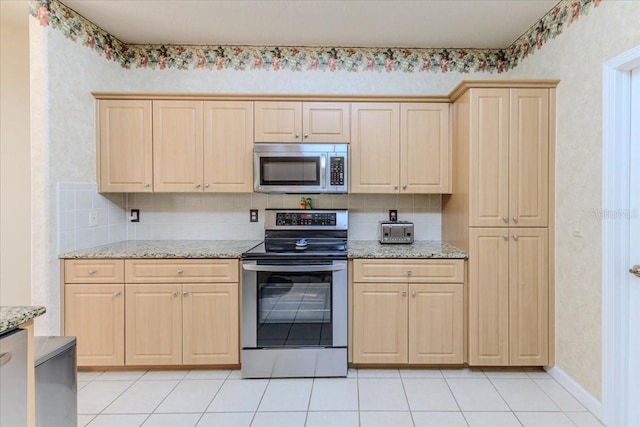 kitchen with light stone counters, stainless steel appliances, tasteful backsplash, and light brown cabinets