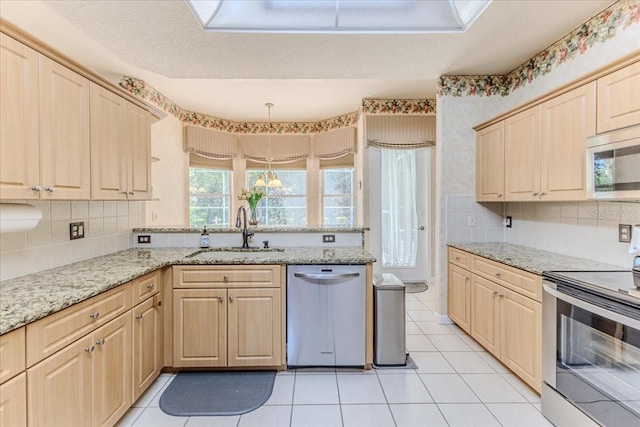 kitchen with light brown cabinetry, a sink, stainless steel appliances, a peninsula, and light tile patterned floors