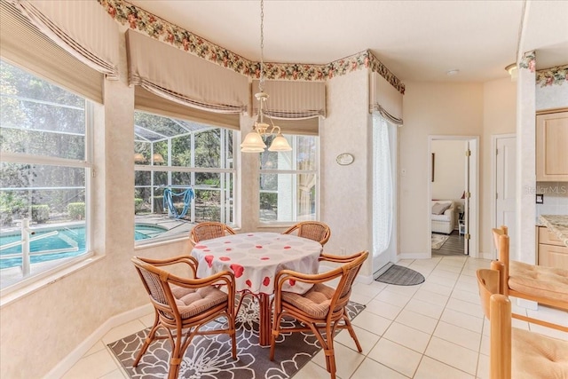 dining space featuring light tile patterned floors, baseboards, and a sunroom