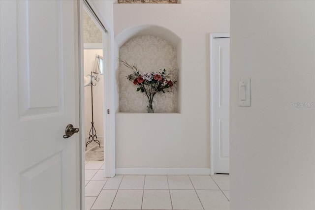 hallway with light tile patterned flooring and baseboards