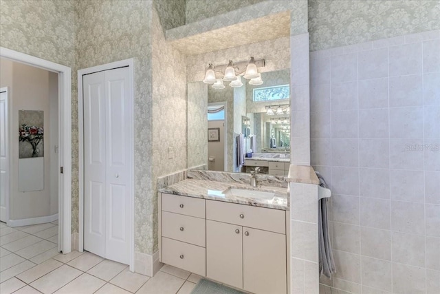 bathroom with wallpapered walls, tile patterned floors, vanity, and a closet