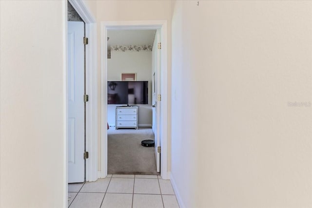 hallway with light tile patterned floors, light colored carpet, and baseboards