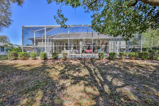 rear view of house with a lanai and an outdoor pool