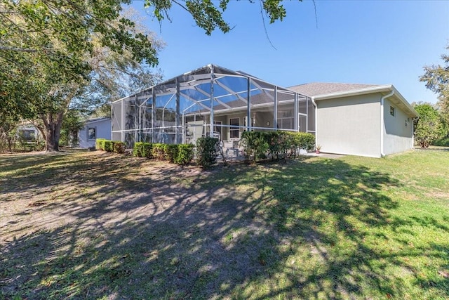 rear view of property featuring stucco siding, a lawn, and glass enclosure