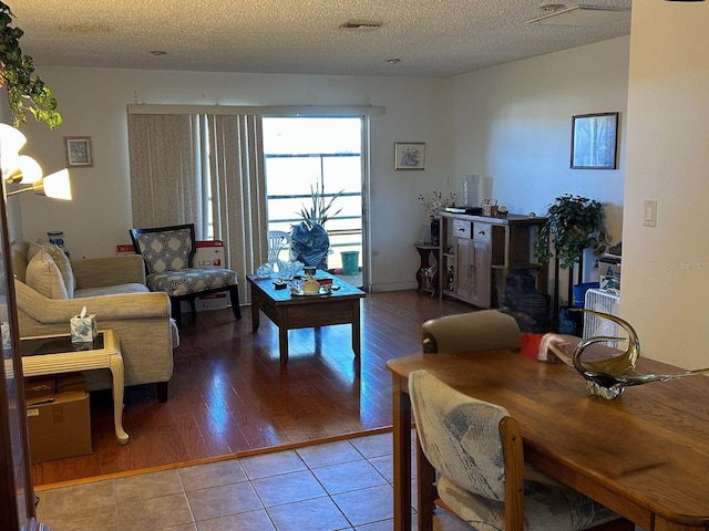 living room featuring tile patterned flooring, visible vents, and a textured ceiling