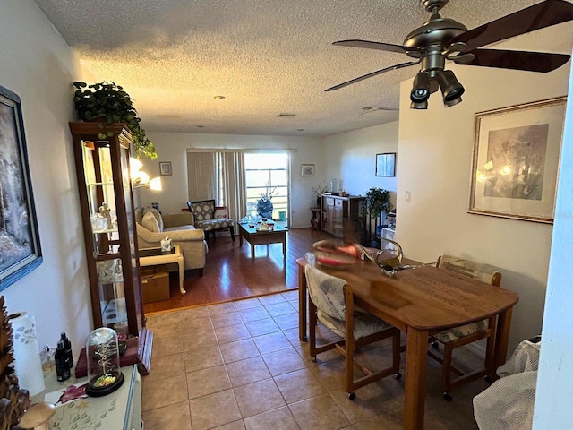 tiled dining area with a ceiling fan and a textured ceiling