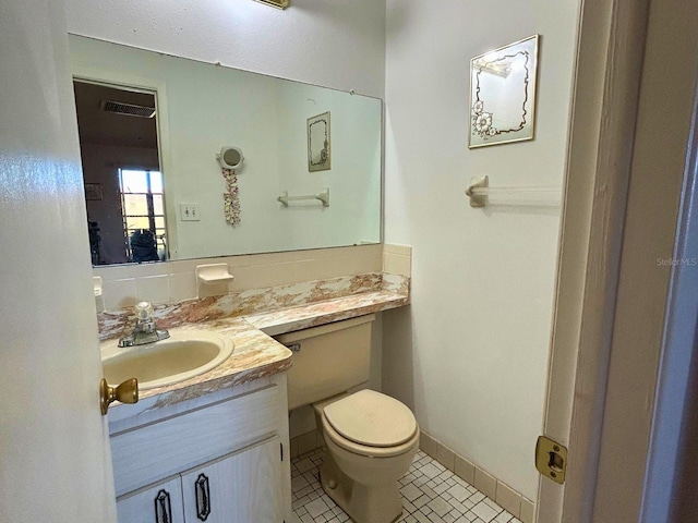 half bathroom with vanity, visible vents, baseboards, tile patterned flooring, and toilet