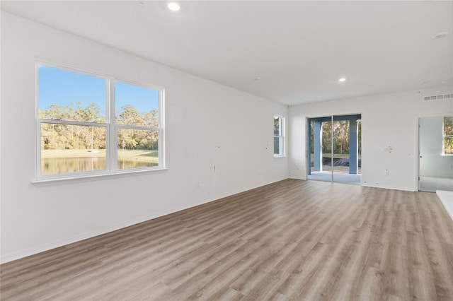 unfurnished living room with recessed lighting, visible vents, a wealth of natural light, and light wood-type flooring