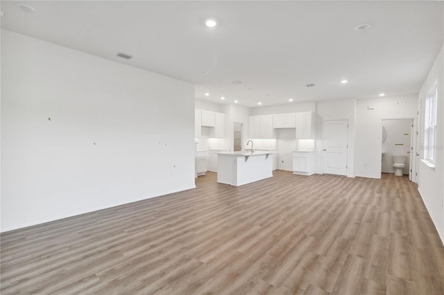 unfurnished living room featuring recessed lighting, light wood-style floors, visible vents, and a sink