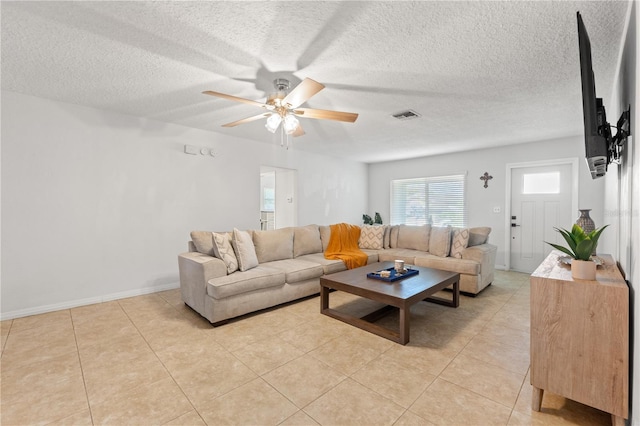 living area featuring light tile patterned floors, visible vents, a textured ceiling, and a ceiling fan