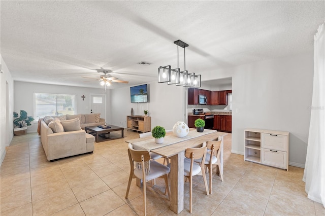 dining area featuring light tile patterned floors, a ceiling fan, visible vents, and a textured ceiling