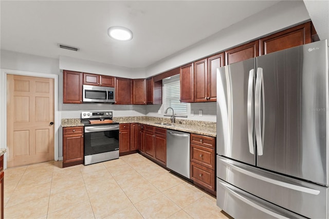 kitchen featuring visible vents, light stone countertops, light tile patterned floors, stainless steel appliances, and a sink