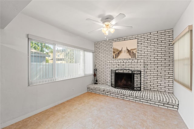 unfurnished living room featuring tile patterned flooring, a brick fireplace, baseboards, and a ceiling fan