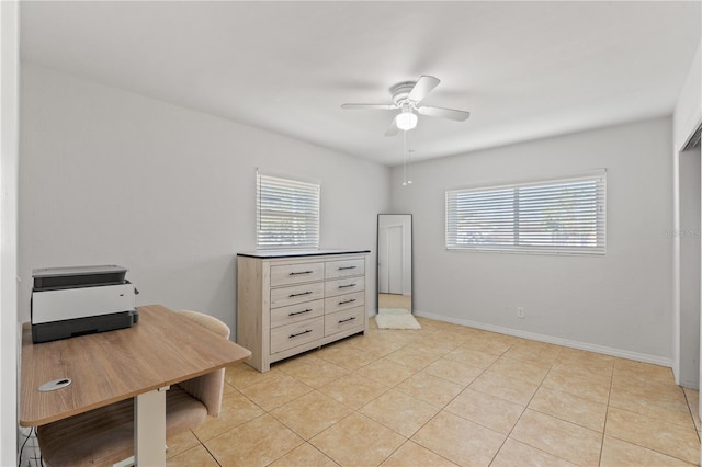 office area featuring a wealth of natural light, light tile patterned floors, baseboards, and ceiling fan