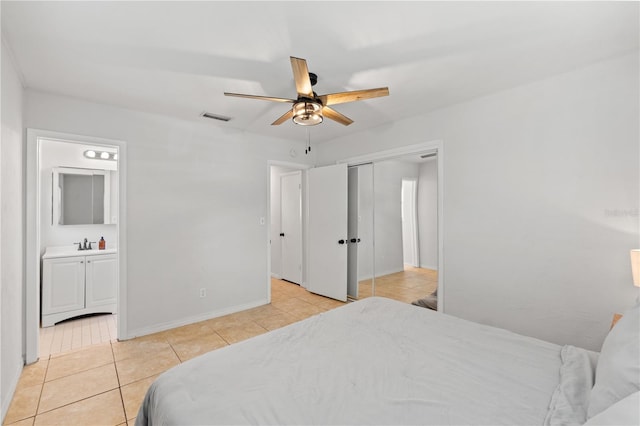 bedroom with baseboards, visible vents, ensuite bath, light tile patterned flooring, and ceiling fan